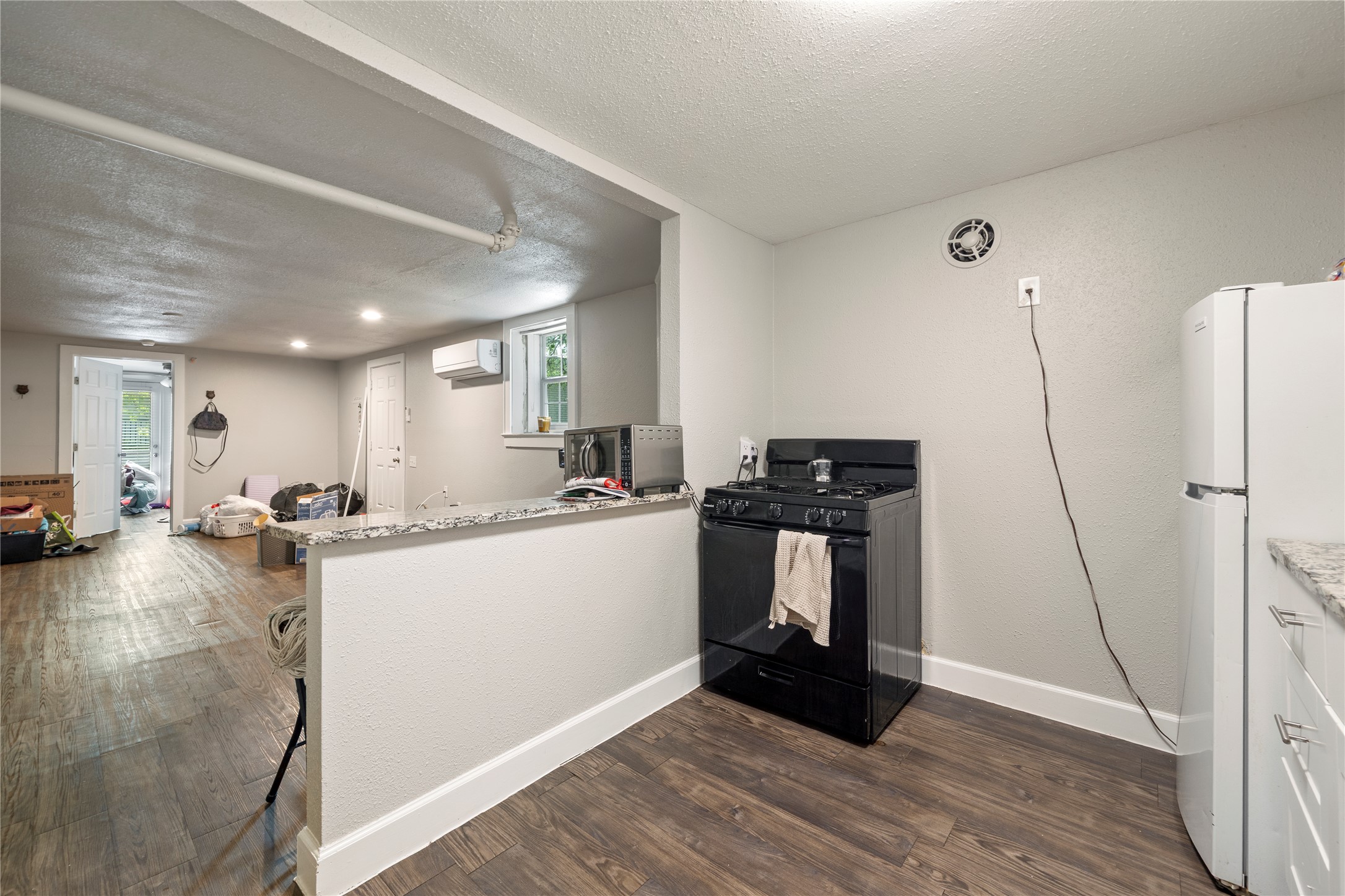 201 West 31st Street, Unit E Austin, TX 78705 - Photo 9 of 16 A compact kitchen with sleek appliances and durable wood flooring.