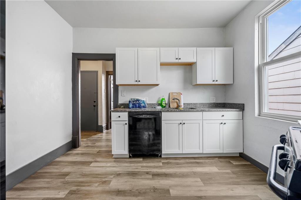 1306 Complete Street Pittsburgh, PA 15212 - Photo 15 of 24 a kitchen with granite countertop a refrigerator stove and white cabinets