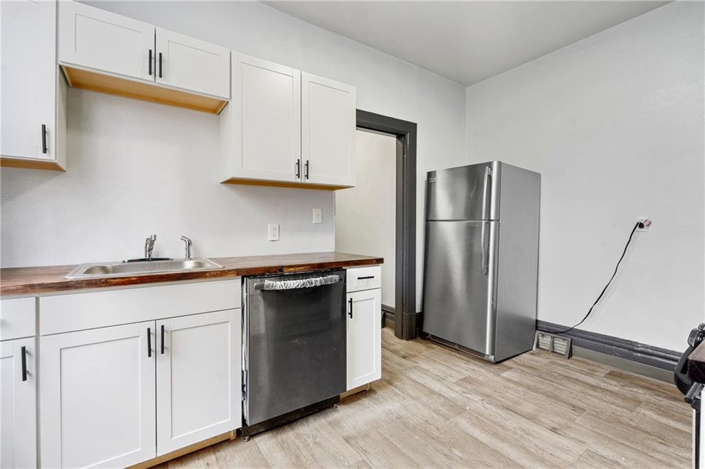 1306 Complete Street Pittsburgh, PA 15212 - Photo 5 of 24 a kitchen with stainless steel appliances granite countertop a refrigerator a sink and white cabinets