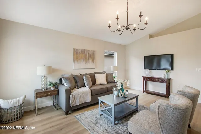 a living room with furniture a chandelier and a flat screen tv
