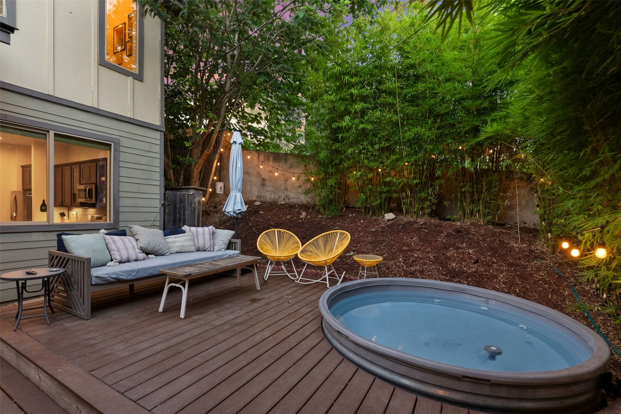 1158 Ridgeway Drive, Unit A Austin, TX 78702 - Photo 22 of 28 A spacious backyard deck offers a private hot tub, lush bamboo landscaping, and string lights for evening ambiance.