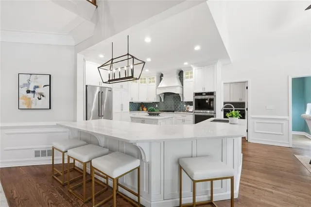 a kitchen with stainless steel appliances a white cabinets wooden floor and a sink
