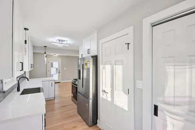a large white kitchen with granite countertop a refrigerator and a sink