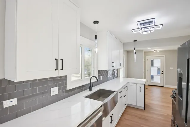 a large white kitchen with a large window and stainless steel appliances