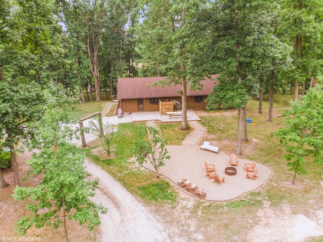a view of a backyard with table and chairs potted plants and large tree