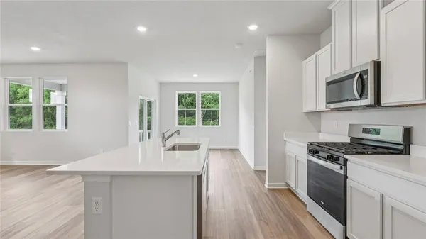 a kitchen with stainless steel appliances a stove a sink cabinets and a wooden floor