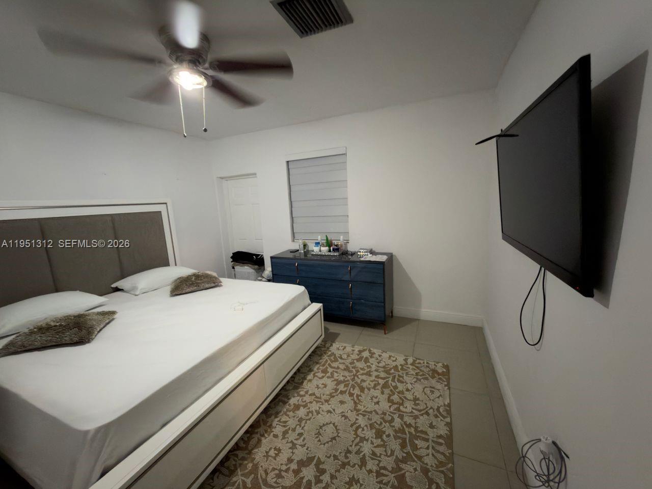 224 East 42nd Street Hialeah, FL 33013 - Photo 31 of 59 a bedroom with a bed and a flat tv screen on the dresser