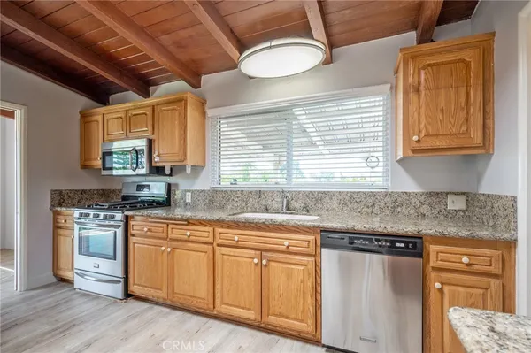 a kitchen with granite countertop white cabinets and white stainless steel appliances