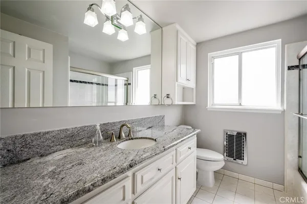 a bathroom with a granite countertop sink a toilet and a mirror