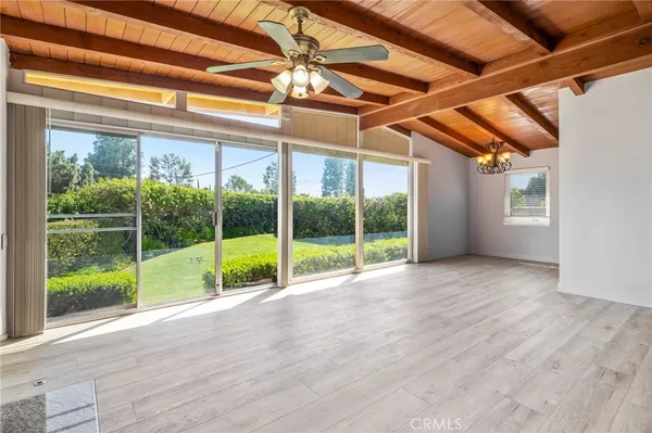a view of an empty room with wooden floor and windows