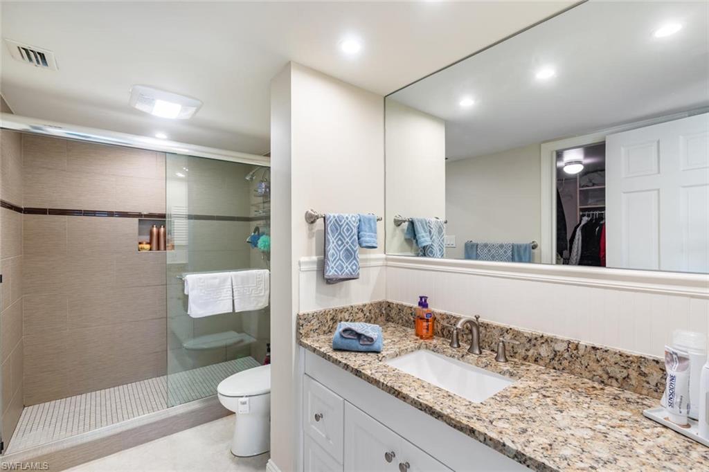 4155 Crayton Road, Unit 201 Naples, FL 34103 - Photo 15 of 24 a bathroom with a granite countertop sink a toilet a mirror and shower