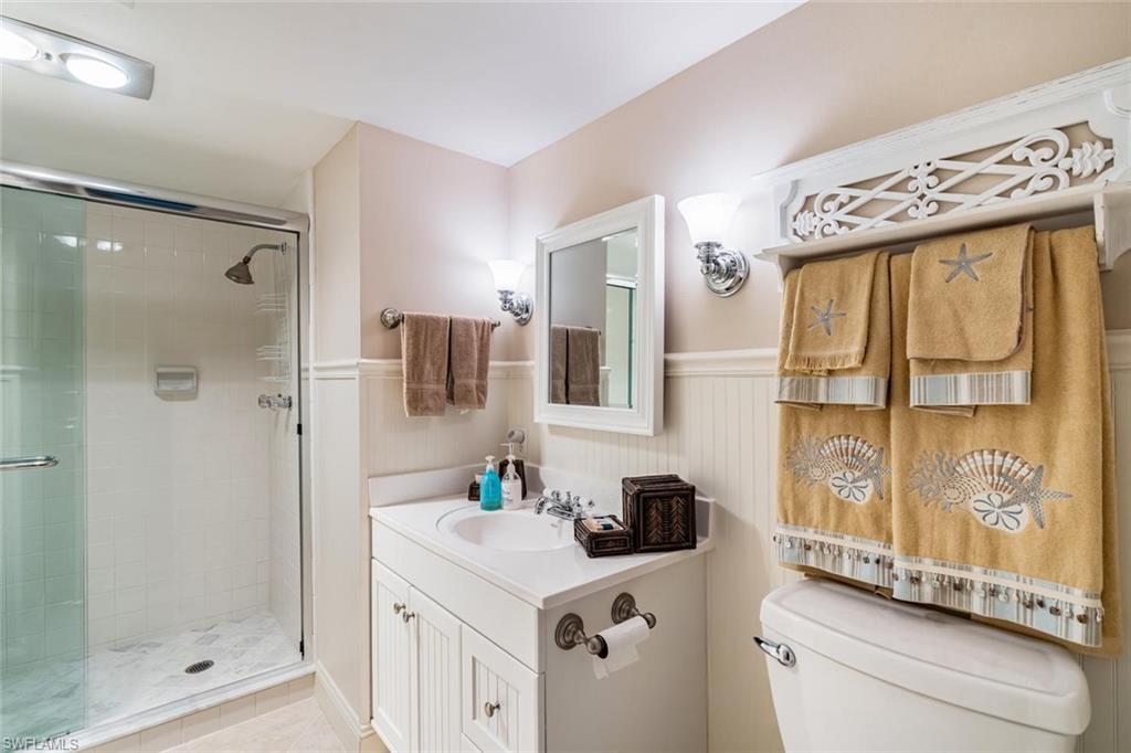 4155 Crayton Road, Unit 201 Naples, FL 34103 - Photo 18 of 24 a bathroom with a granite countertop sink a mirror and a shower