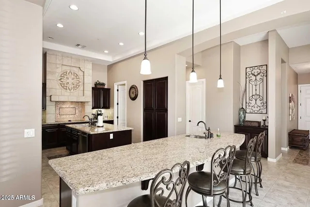 a kitchen with granite countertop kitchen island stainless steel appliances a sink stove and white cabinets