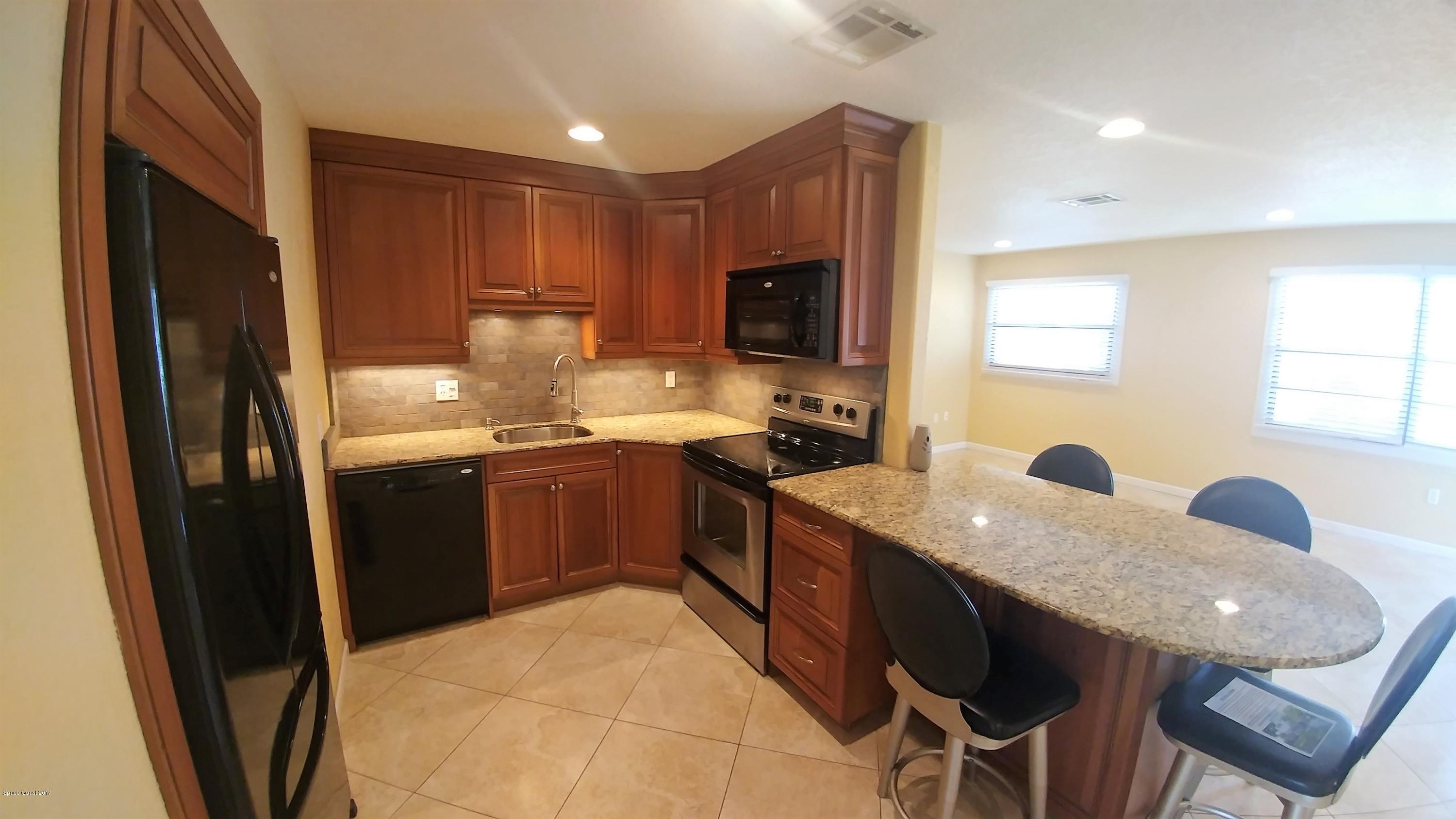 2857 Tropic Road Melbourne, FL 32935 - Photo 12 of 28 a kitchen with stainless steel appliances granite countertop a sink a stove a refrigerator a microwave a dining table and chairs
