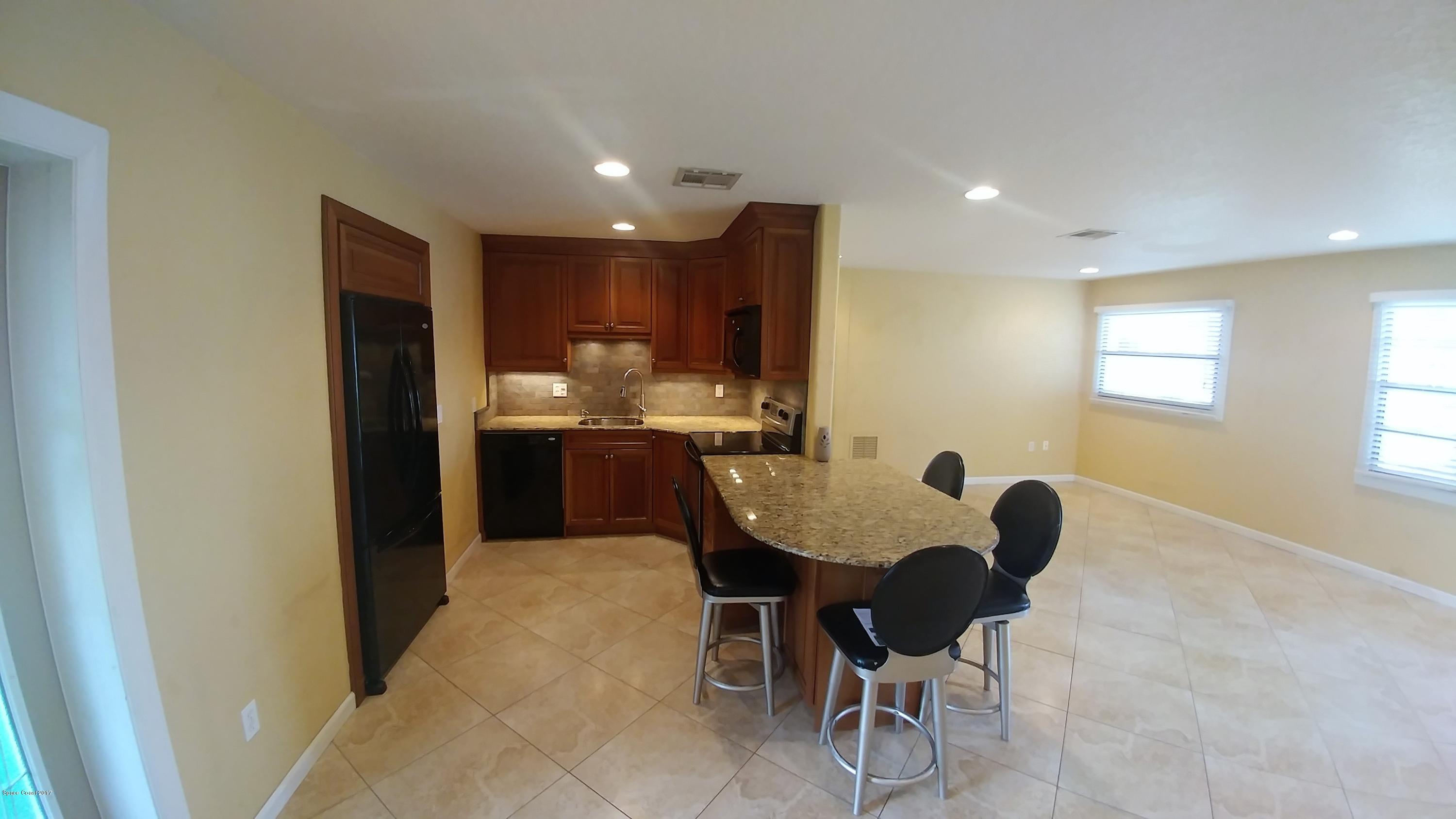 2857 Tropic Road Melbourne, FL 32935 - Photo 15 of 28 a kitchen with kitchen island a dining table chairs stainless steel appliances and cabinets