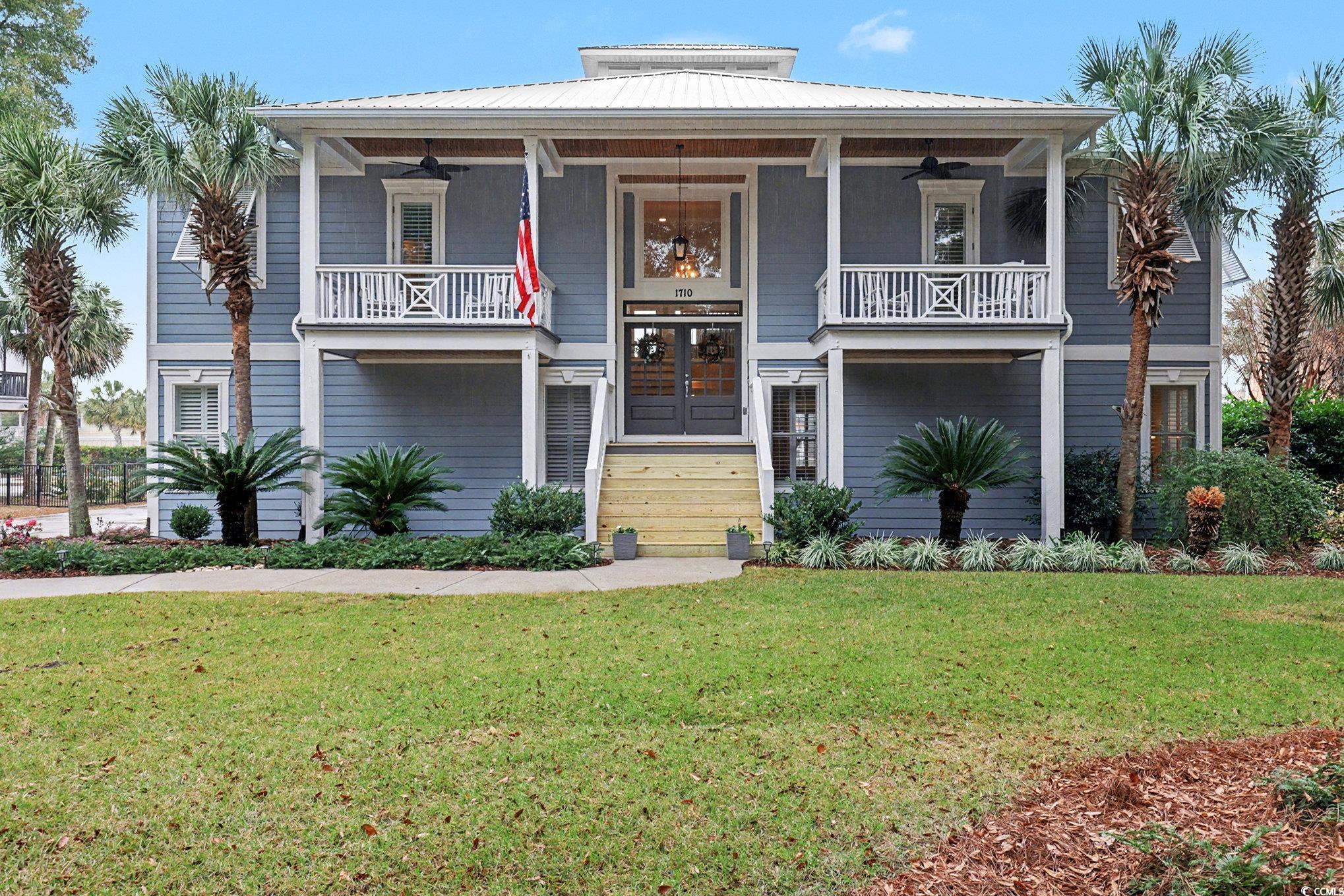 Coastal home featuring a metal roof, a front yard, and a ceiling fan