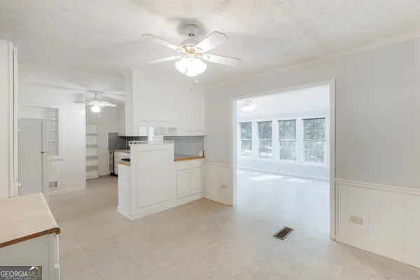 a view of an empty room with a window and a kitchen