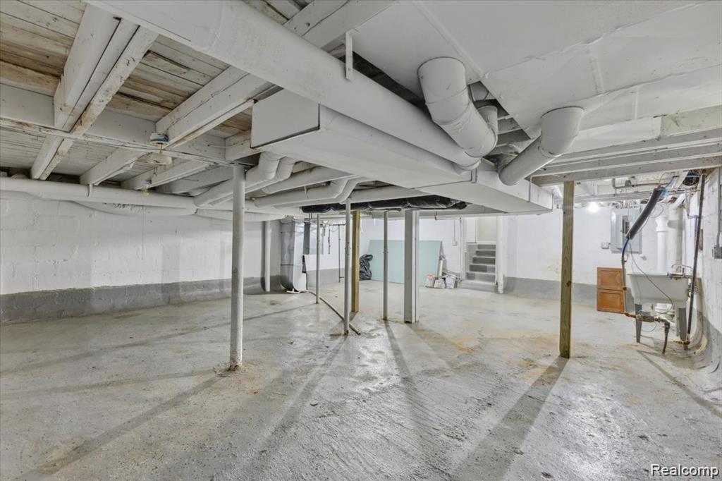 3140 Moore Street Inkster, MI 48141 - Photo 16 of 18 Spacious basement featuring painted concrete block walls, exposed wood ceiling joists, concrete flooring, support columns, and overhead utility piping