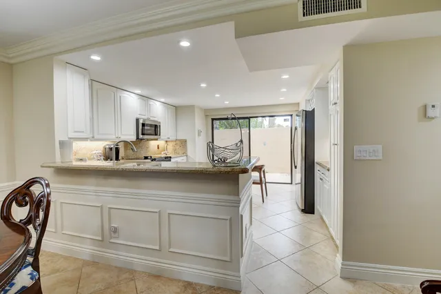 a kitchen with white cabinets and refrigerator