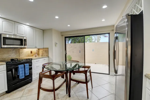 a kitchen with stainless steel appliances granite countertop a stove top oven a sink dishwasher a dining table and chairs with wooden floor