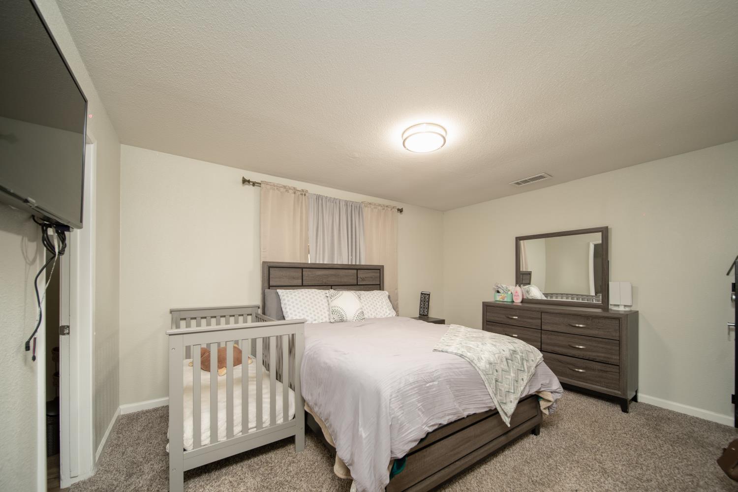 601 Summit Court Modesto, CA 95357 - Photo 11 of 17 a bedroom with a bed and a flat tv screen on the dresser