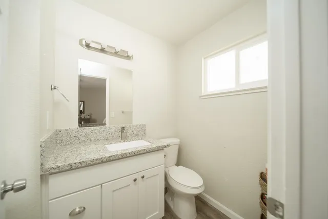 a bathroom with a granite countertop sink a toilet and a mirror