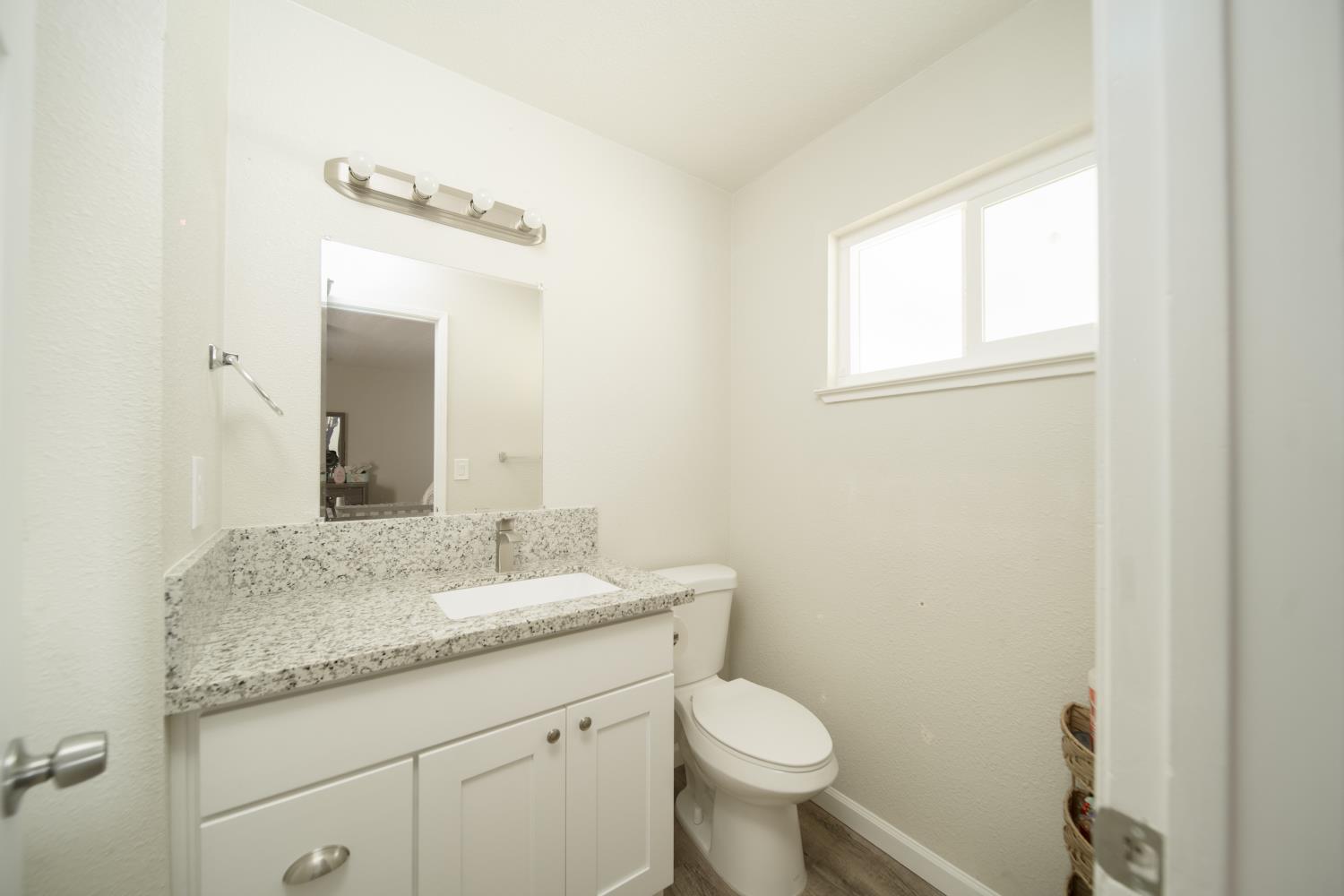 601 Summit Court Modesto, CA 95357 - Photo 12 of 17 a bathroom with a granite countertop sink a toilet and a mirror