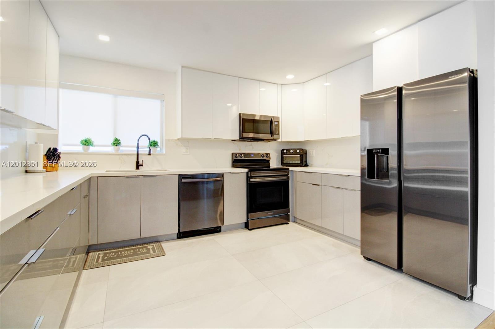 360 Northeast 116th Street Miami, FL 33161 - Photo 18 of 29 a kitchen with a refrigerator a sink and a stove top oven