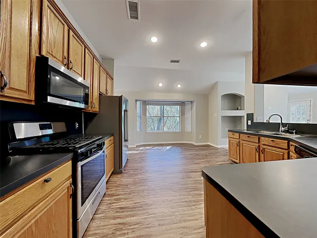 a kitchen with stainless steel appliances granite countertop a sink wooden cabinets and granite counter tops