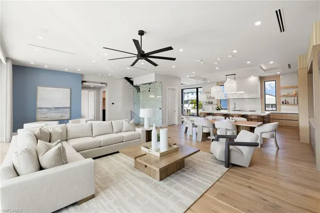 a living room with furniture kitchen view and a wooden floor