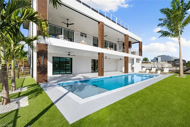a view of a white house with a yard table and chairs
