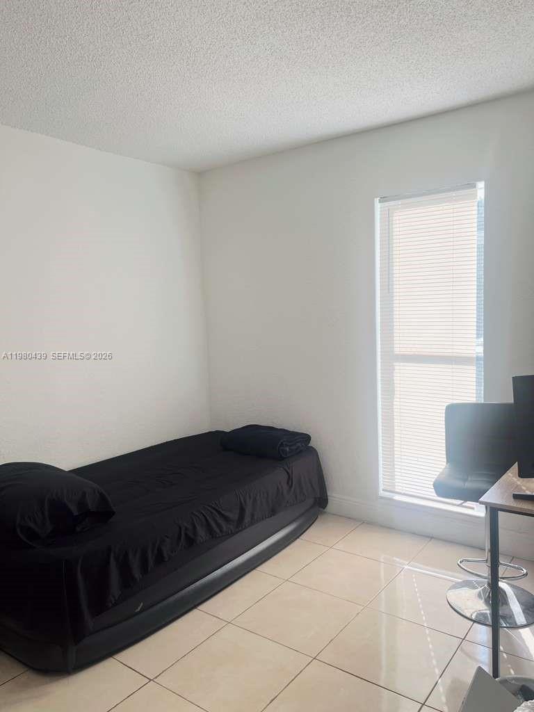 4435 Treehouse Lane, Unit H Tamarac, FL 33319 - Photo 17 of 18 a bedroom with a bed and chair