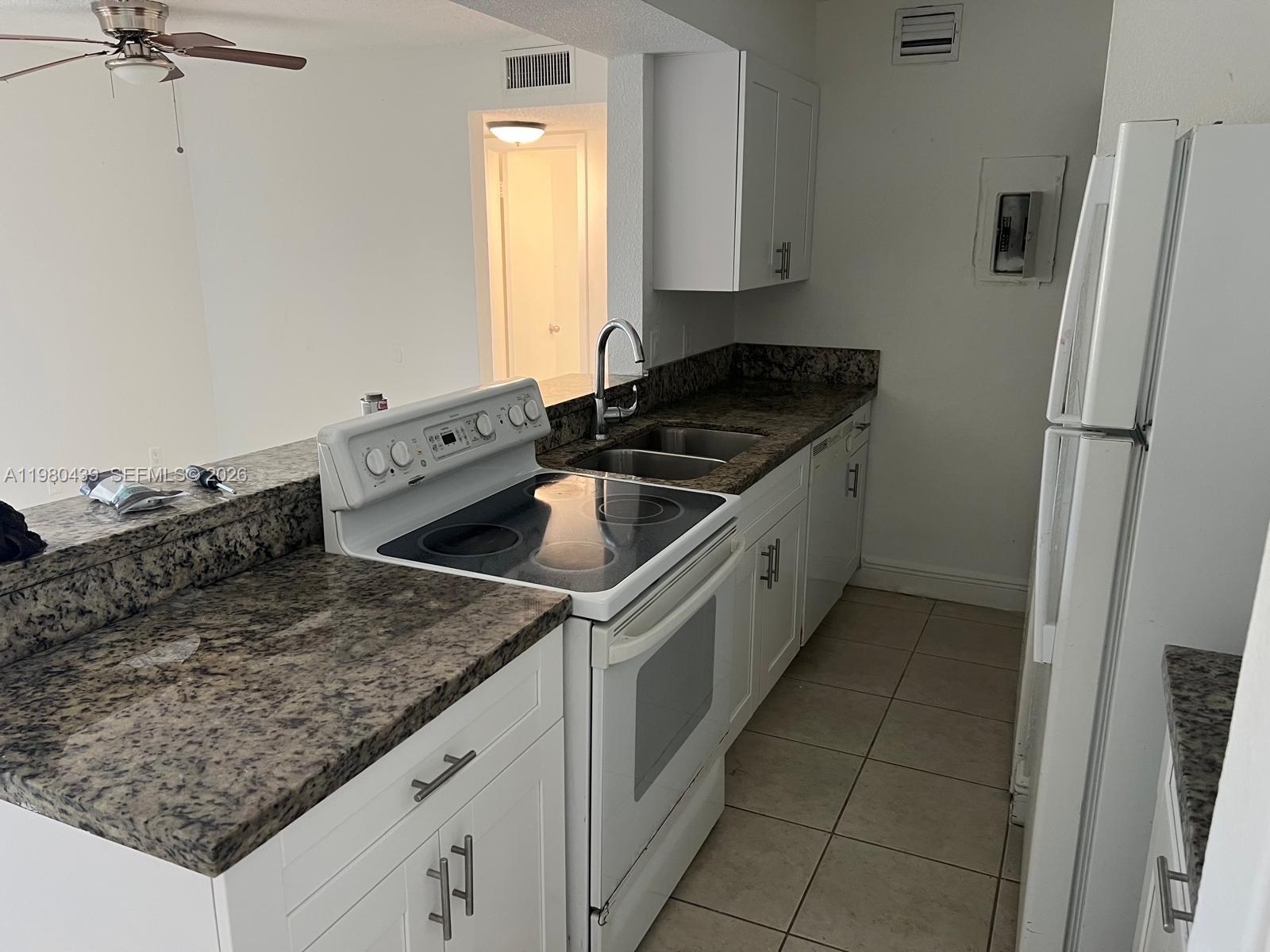 4435 Treehouse Lane, Unit H Tamarac, FL 33319 - Photo 3 of 18 a kitchen with a sink stove and refrigerator