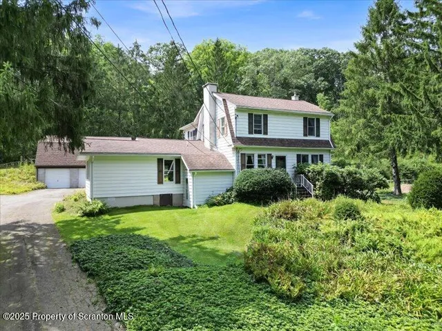 a view of a white house with large windows and a small yard