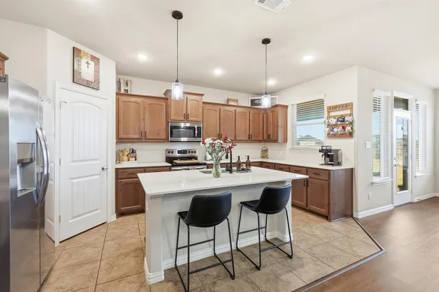 a kitchen with kitchen island granite countertop a center island a refrigerator a stove a dining table and chairs