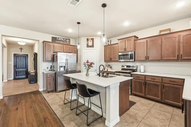 a kitchen with stainless steel appliances granite countertop a sink a stove a refrigerator and island with wooden floor