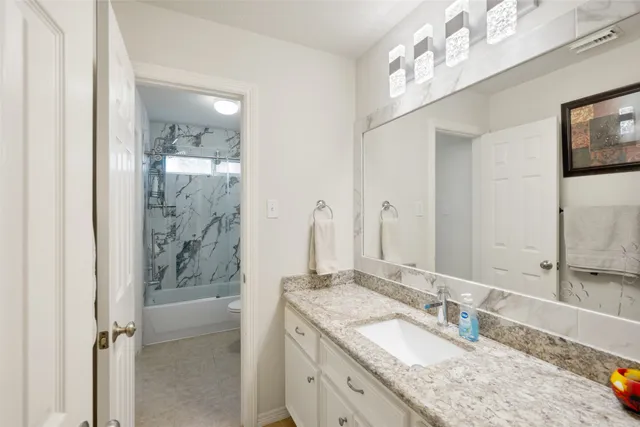 a bathroom with a granite countertop double vanity sink mirror and shower