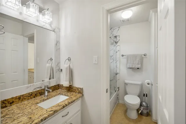a bathroom with a granite countertop sink toilet and shower