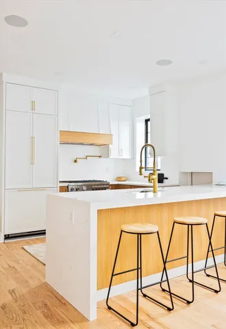 a kitchen with a sink a stove and white cabinets with wooden floor