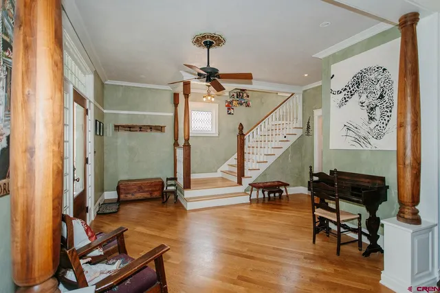 a view of a hallway with couches and a dining table with wooden floor