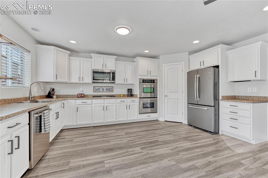 1064 Diamond Rim Drive Colorado Springs, CO 80921 - Photo 8 of 30 a kitchen with granite countertop white cabinets and stainless steel appliances