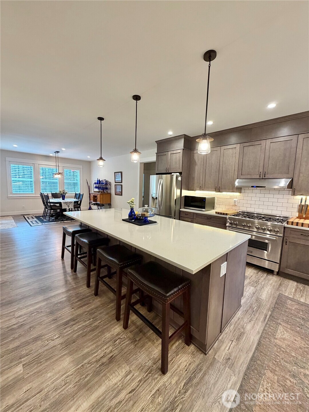 18349 Northwest Stavis Bay Road Seabeck, WA 98380 - Photo 15 of 40 a kitchen with stainless steel appliances kitchen island granite countertop a table chairs and a wooden floors