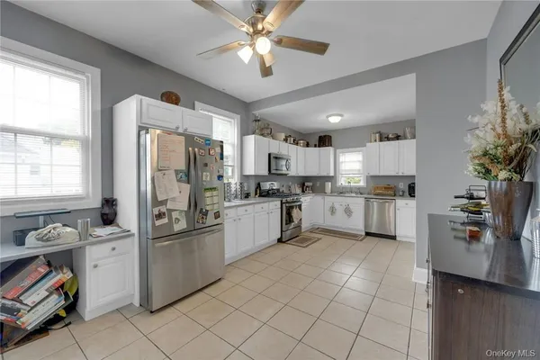 a kitchen with a refrigerator a sink dishwasher stove and white cabinets