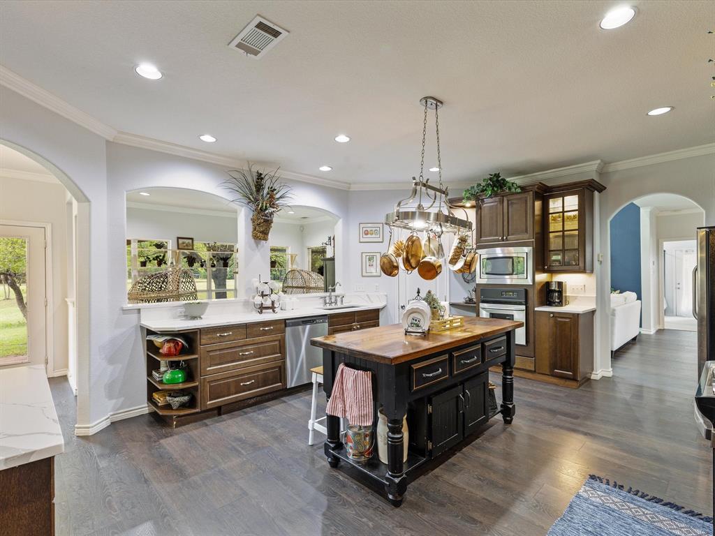 1514 New Market Road Mesquite, TX 75149 - Photo 22 of 30 a kitchen island with stainless steel appliances granite countertop center island and a wooden floor