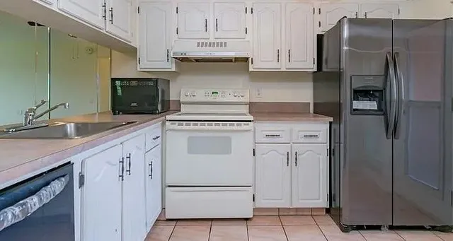 a kitchen with white cabinets and refrigerator