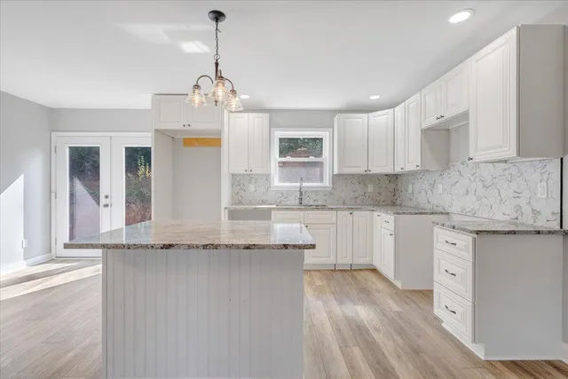 a kitchen with stainless steel appliances granite countertop a sink stove and white cabinets