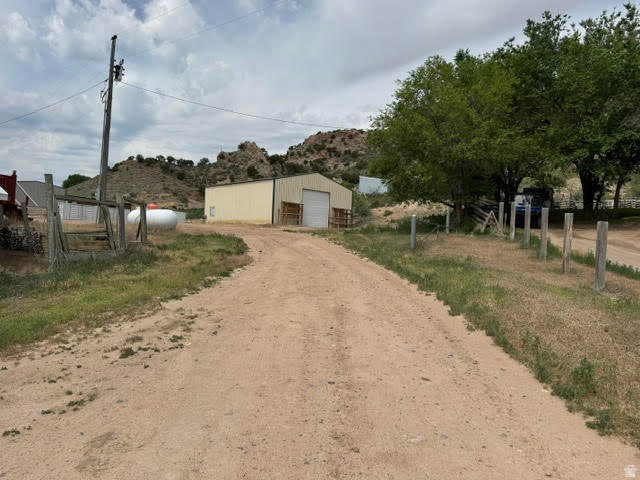 1124 Washam Road Green River, WY 82938 - Photo 11 of 35 Expansive dirt driveway leading to a large metal building with a roll-up door