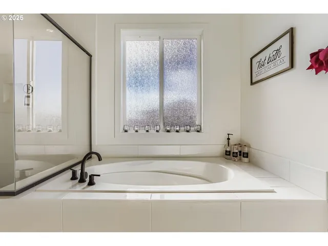 a bathroom with a tub a sink and a mirror