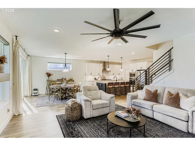 a living room with furniture kitchen view and a wooden floor