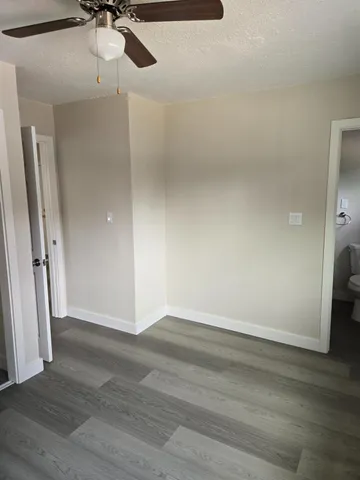 a view of a room with wooden floor and a ceiling fan
